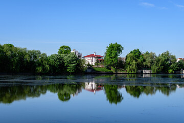 Obraz premium Landscape with old green trees near Mogosoaia lake and park, a weekend attraction close to Bucharest, Romania, in a sunny spring day.