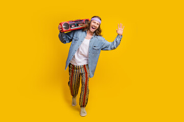 Full size photo of cool young man dance boombox empty space wear denim shirt isolated on yellow color background