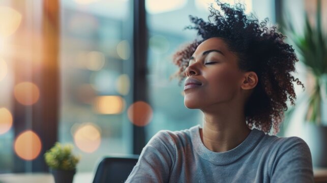 A person sits at their desk with their eyes closed taking a break from work to refocus and engage in mindful breathing.