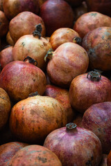 Purple pomegranates background, vertical. Ripe pomegranates on market. Juicy fruits.  Vitamin and antioxidant. Summer harvest. Fruits on commercial showcase. Pile of pomegranates.