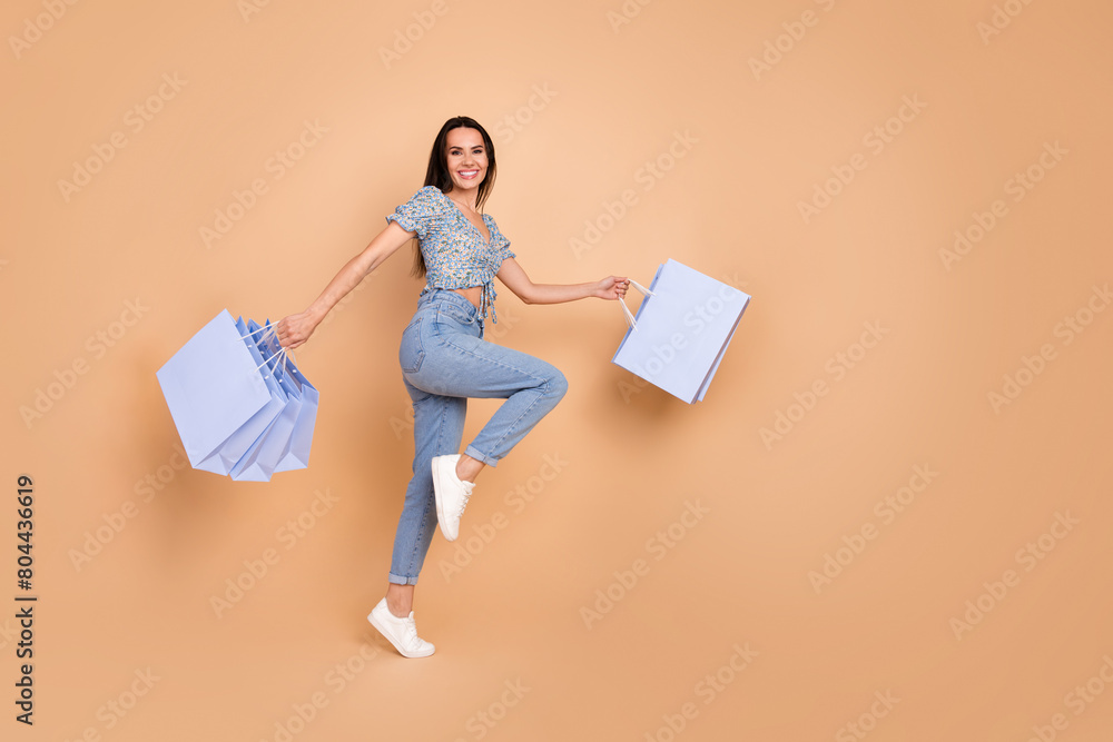 Wall mural photo of funny cute cheerful woman wear blue trendy outfit hold packages purchase blank space isolat