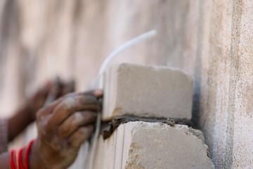Closeup of a construction worker installing and measuring a concrete block on a wall