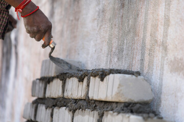 A focused construction worker meticulously smooths a layer of plaster onto a brick wall