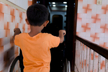 Asian boy with wheelchair standing in front of the door at home