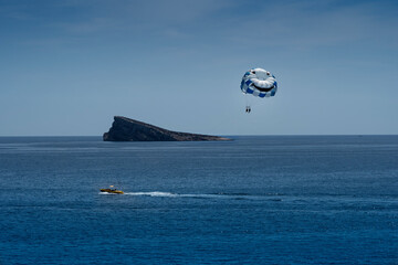 Parasailing - a parachute, a boat, an unforgettable experience and Isla de Benidorm in the background. Smile concept