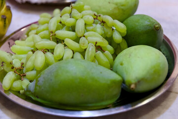 Green mangoes and grapes on a metal plate Selective focus