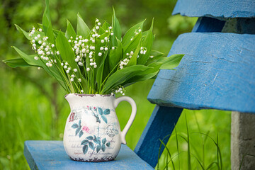 Bouquet of spring lily of the valley flowers on a bench in the garden