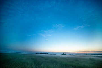 night photo. start of the day. dawn.fields and forest on the horizon in the fog and stars in the...