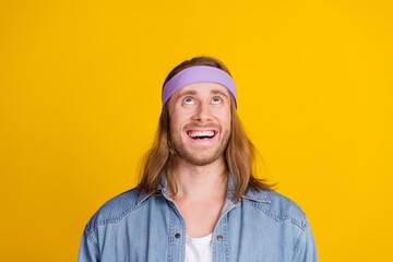 Photo portrait of attractive young hippie man look up excited empty space wear trendy denim outfit isolated on yellow color background