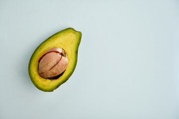 Sliced green unripe not ready to eat avocado fruit or vegetable with peeled off seed with knife...