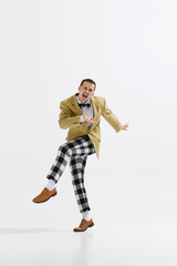Lively young male dancer dressed in retro-inspired checkered pants and jacket performing, dancing...