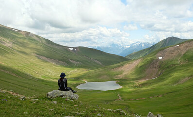 beautiful Summer landscape with sitting relaxing tourist in mountains. rear view. scenic nature...