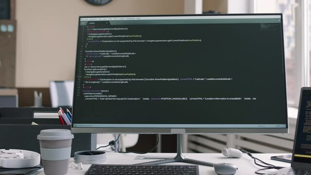 No people shot of html program code running on black screen of desktop computer monitor at desk in modern IT office