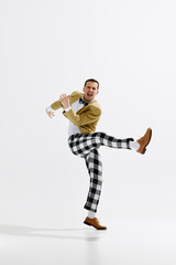 Joyful male performer in stylish outfit with checkered pants and jacket captured mid-dance pose...