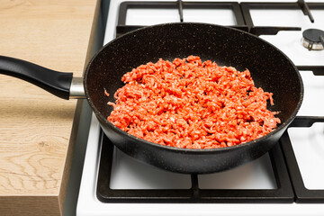 fresh minced meat lies on a frying pan