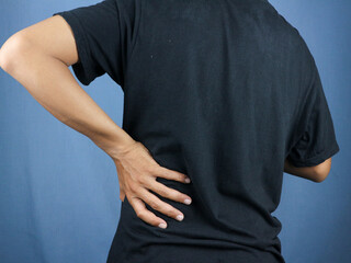 Close-up rear view of man's hand touching back pain, low back pain concept.