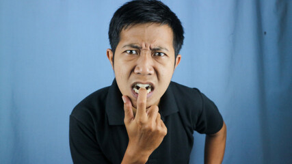 portrait of funny face expression of asian man surprised and biting finger.