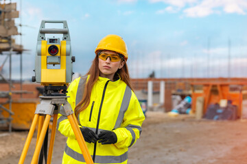 serious graduate female site engineer surveyor working with theodolite EDM equipment on building...