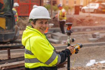 happy mature woman site engineer surveyor working with theodolite equipment on building site
