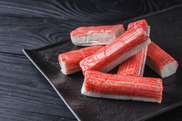 fresh chilled surimi crab sticks on black wooden background