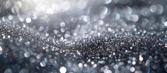 A blurred image featuring a black and white background with sparkling silver particles creating a bokeh effect.