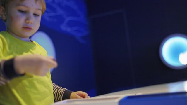 A young boy is sitting at a table with a blue box in front of him