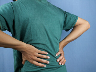 Close-up rear view of man's hand touching back pain, low back pain concept.
