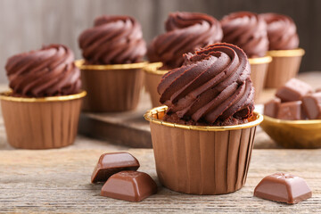 Delicious cupcakes and chocolate pieces on wooden table, closeup