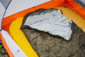 A sleeping bag rests on a yellow mattress inside a tent