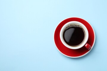 Aromatic coffee in cup on light blue background, top view. Space for text