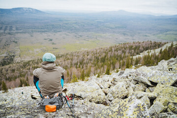 a man is sitting on top of a rocky mountain looking at the landscape