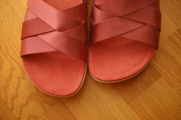 Pair of red sandals on a wooden floor. Close-up