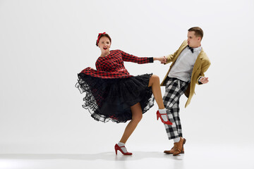 Stylish and playful couple in 1950s style clothes performing dynamic dance, expressing joy and...