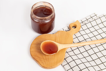 Jam in a glass jar on wooden board. Jam in wooden spoon