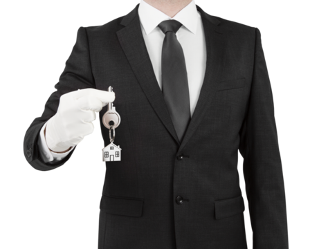A person in a suit holding house keys on a white background, concept of real estate