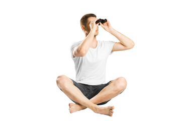 A man sitting cross-legged and looking through binoculars, isolated on a white background,...