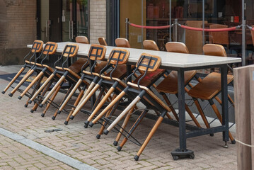 Chairs lying on tables in an outdoor closed bar

