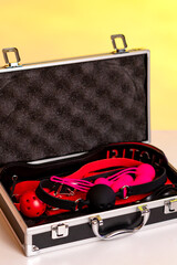 Sex toys for adults in a box. Suitcase with sex toys in black and red. Whip, gags, handcuffs, Kegel...