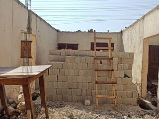 Rebuilding History: Concrete Blocks and Wooden Ladder in Old House Restoration