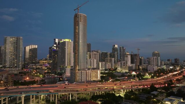 Aerial view of cars driving on Downtown I95 Riverside multilane highway at night with Miami skyline view. Drone flight over rush hour traffic on the highroad in Miami