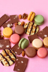 Pastel macarons, almond chocolate, peanut butter cookies and various nuts on bright pink background. Selective focus.