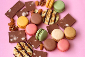 Pastel macarons, almond chocolate, peanut butter cookies and various nuts on bright pink background. Selective focus.