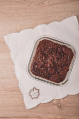 baked brownie on glass baking dish with cacao nibs topping over vintage table cloth
