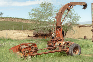 An old, rusty combine harvester sits in a field. The combine harvester is old and rusted, and it is...