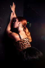 Beautiful go-go dancer in a leopard print top and black skirt posing in a nightclub. atmospheric light. Party concept, nightclub