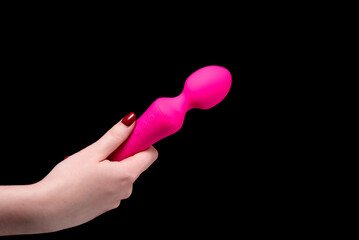 Pink dildo for masturbation in a girl's hand on a black background. Sex Shop Adult Shop