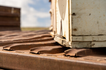 A rusty metal box with a white lid sits on a metal platform. The lid is slightly open, revealing a...