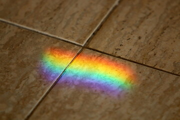 A multi-colored sunbeam is reflected on the tiles.
