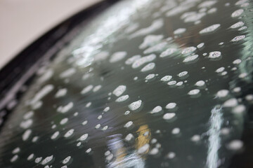 Closeup of windshield with water drops, showing moisture on auto part