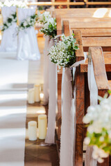 wedding decoration of pews in the church. Small gypsophila bouquets with chiffon ribbons